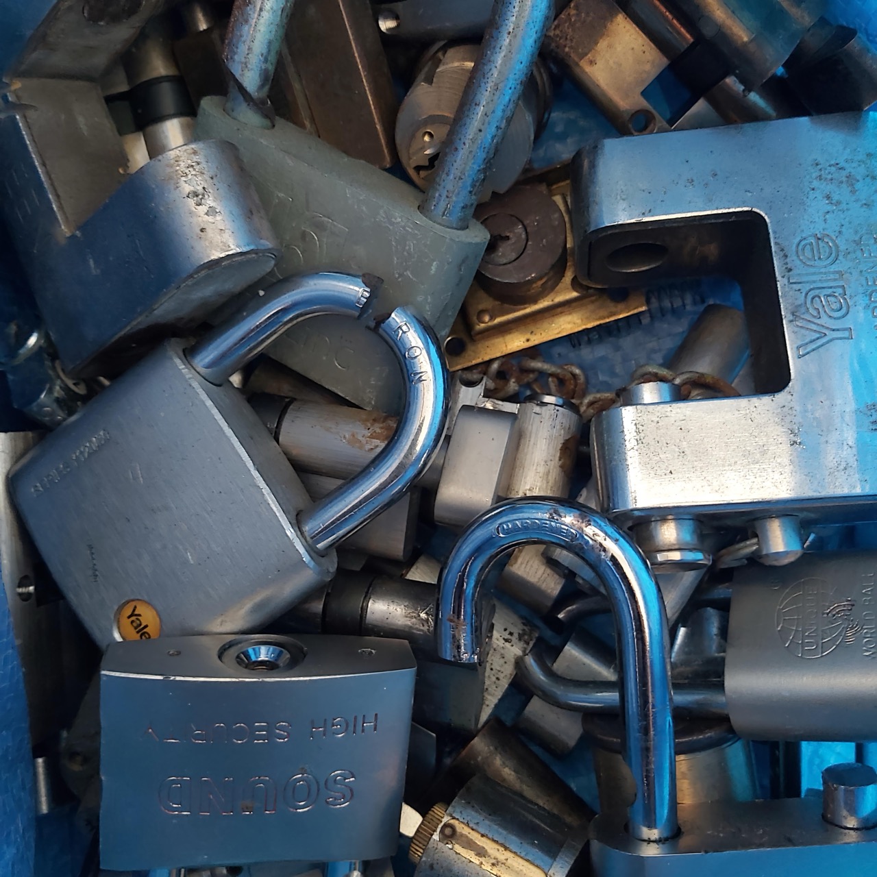 Pile of discarded padlocks (Yale, Sound) collected after replacement jobs.